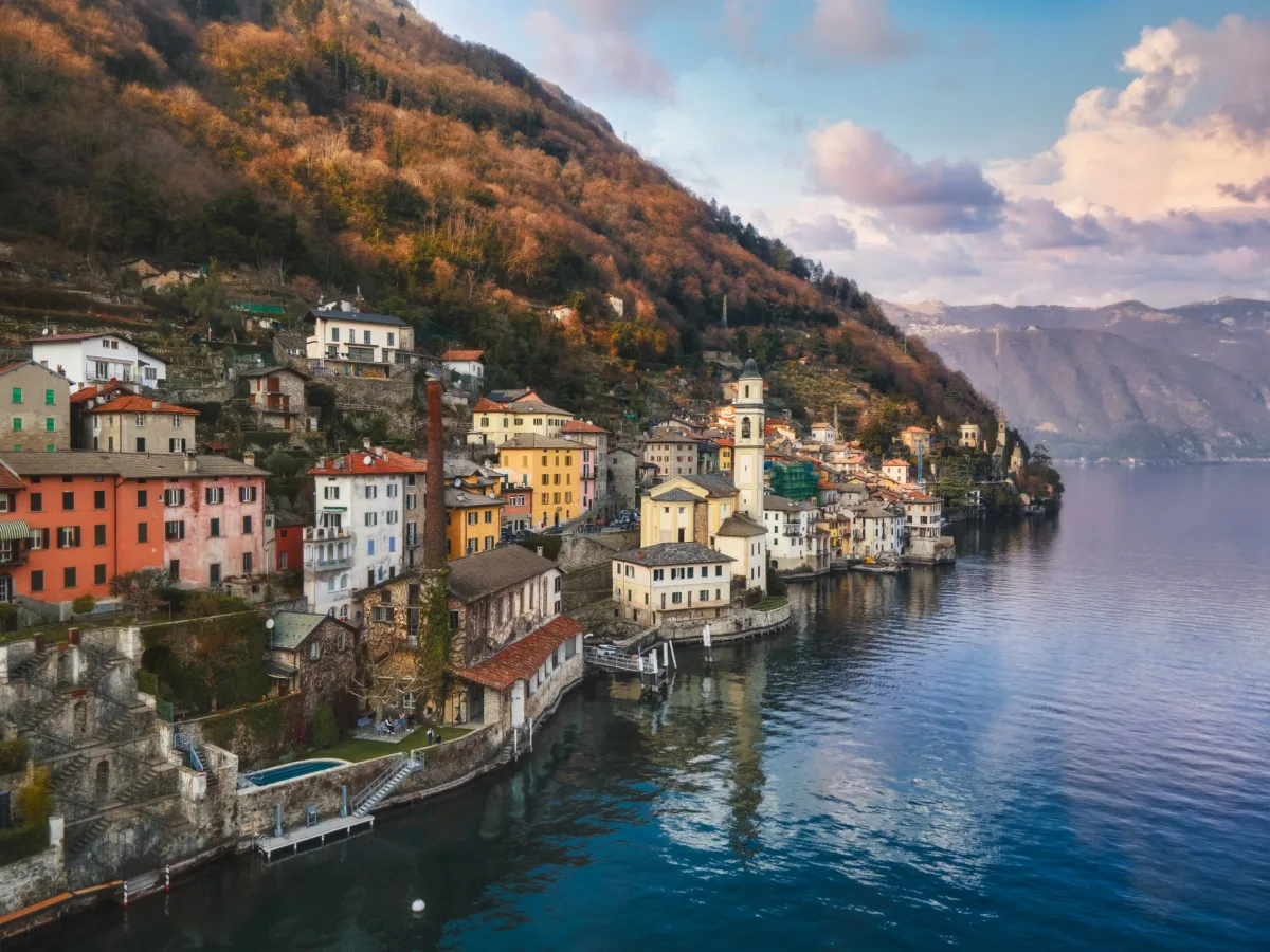 A picturesque aerial view of a charming town along Lake Como, surrounded by mountains and