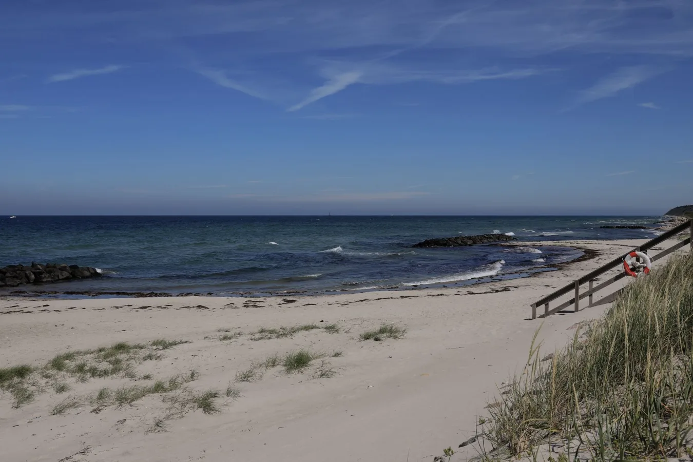 Serene beach in Denmark with sandy shores, wooden stairs, and clear blue skies. Perfect su