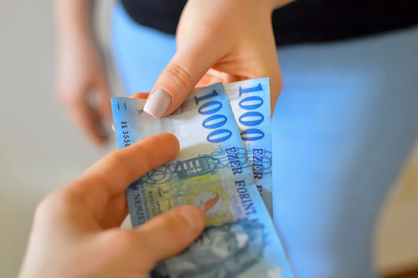 An exchange of 1000 Hungarian Forint banknotes between two hands.