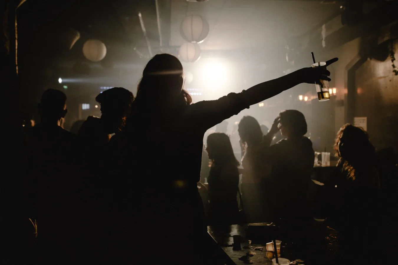 Silhouettes of people dancing and enjoying drinks at a bustling nightclub.