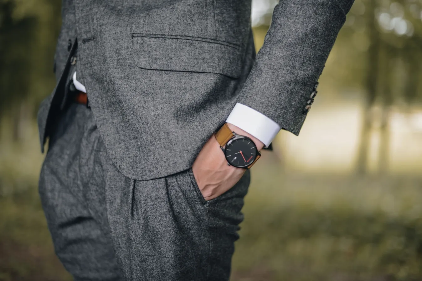 Close-up of a man in a tailored suit wearing an elegant wristwatch outdoors, exuding fashi
