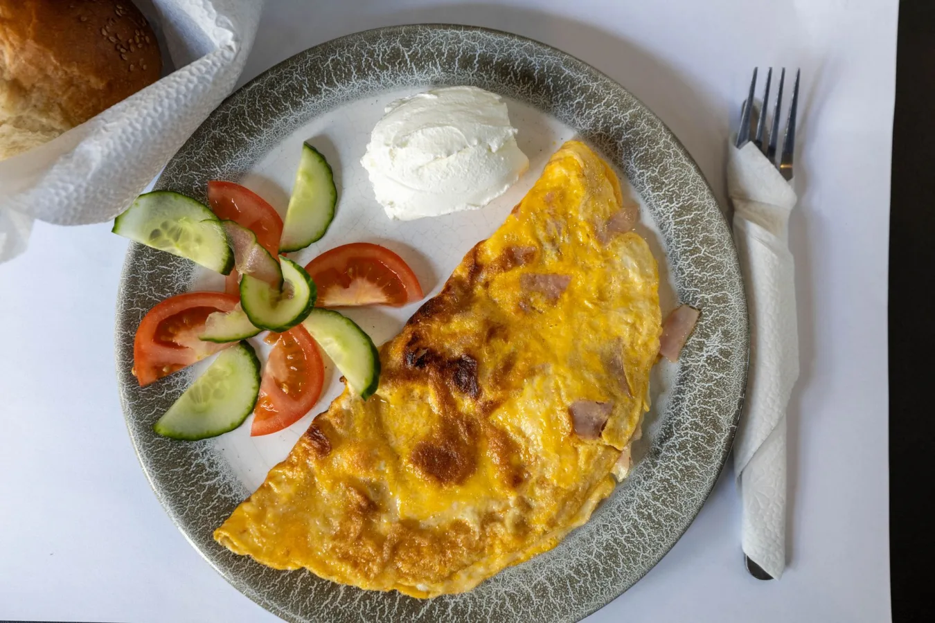 Top view of an omelette with cucumbers and tomatoes, perfect breakfast setting.