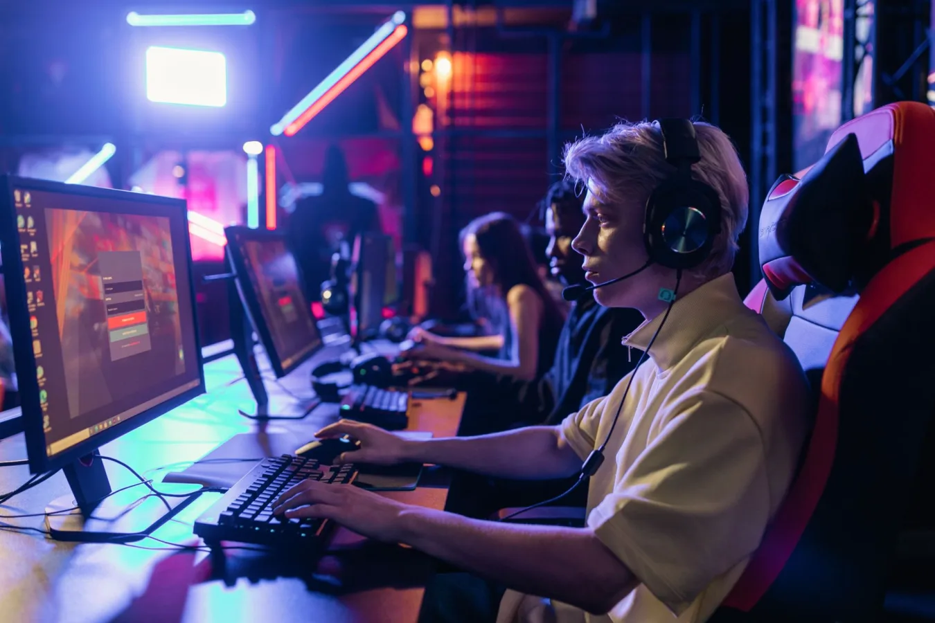 Gamers engaged in a competitive session, equipped with headsets and monitors in an immersi