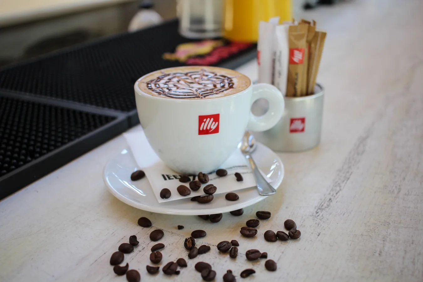 Cup of illy branded coffee with latte art on a wooden table in a café.