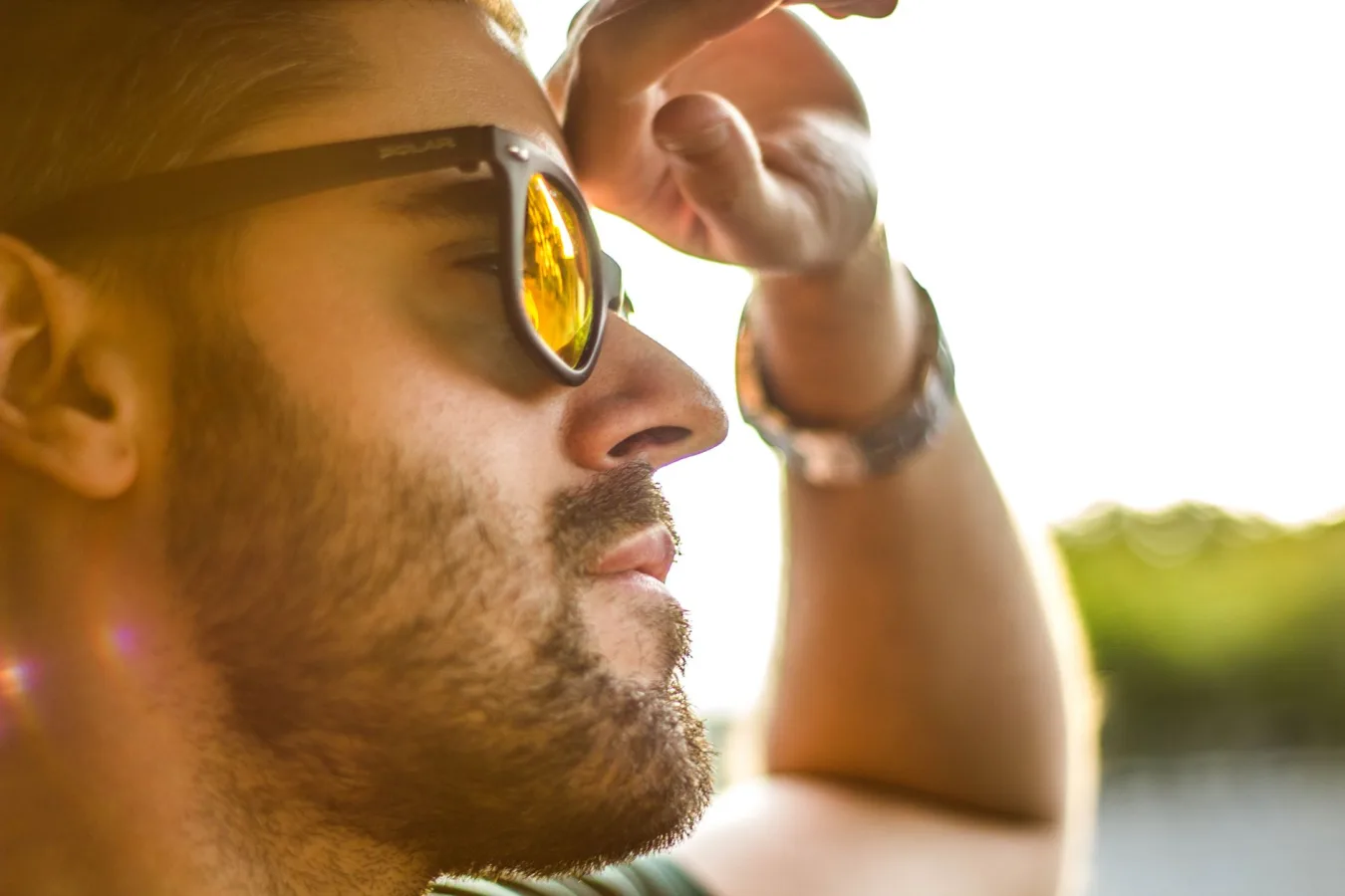 Close-up of a bearded man wearing sunglasses, enjoying a sunny day outdoors.