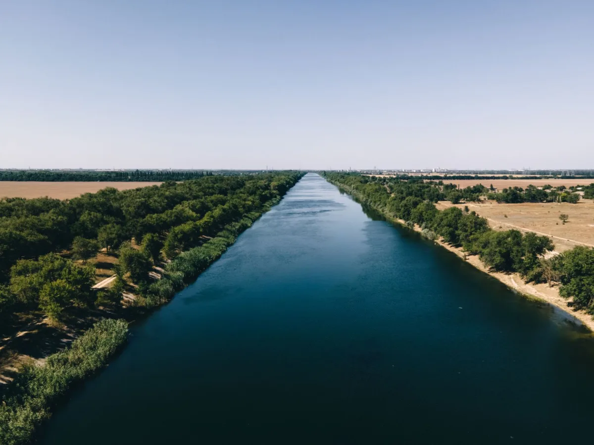Drone shot capturing a tranquil river flanked by lush greenery in a rural landscape under