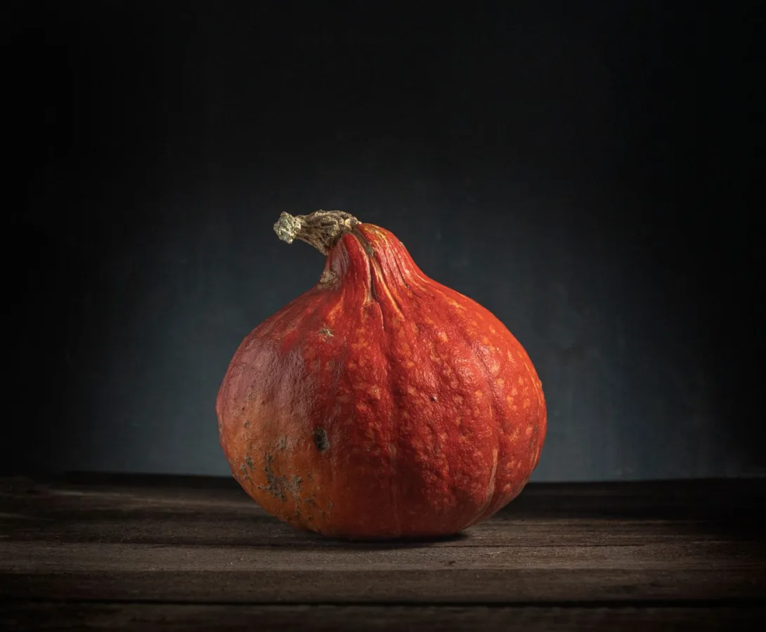 A solitary orange pumpkin sits on a rustic wooden table, embodying the essence of fall dec
