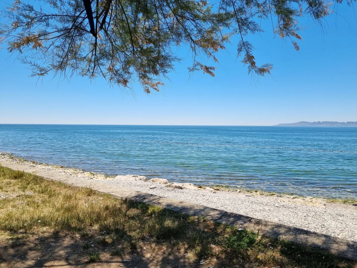Tranquil beach view with clear blue sky and calm sea, perfect for summer vibes.