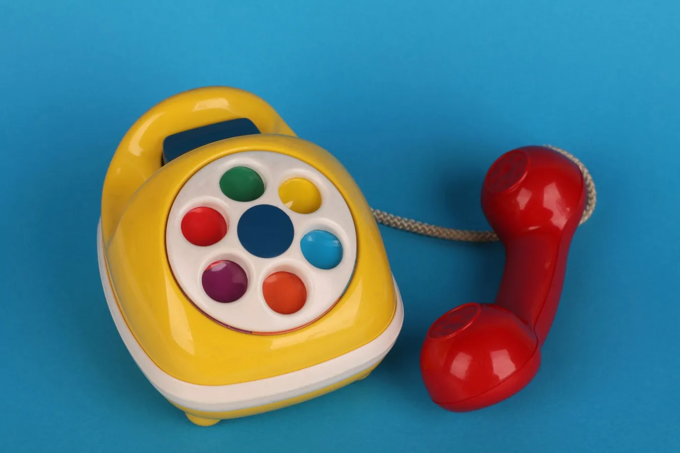 Brightly colored vintage toy telephone on a blue background, showcasing its vibrant design