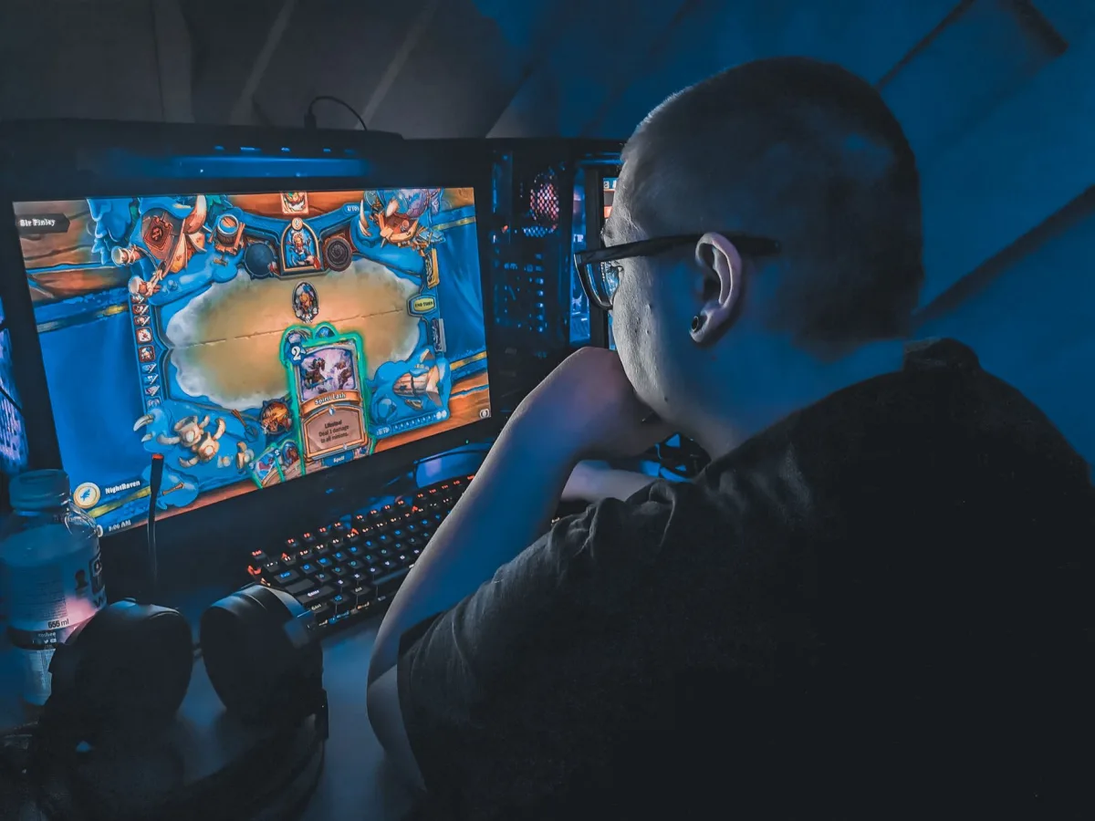 High angle of plump male gamer thinking and playing video game while sitting at table unde